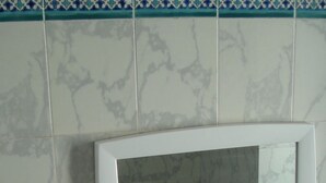 Ein Badezimmer mit einem weißen Waschbecken, einem Spiegel und einem grünen Seifenspender auf einem weißen Regal.