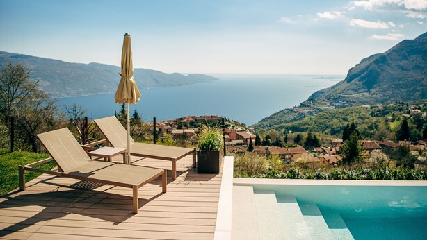 A wooden deck with lounge chairs and a pool overlooking a scenic view of a lake and mountains. - Apartment with breakfast - Only Adults (Tignale)