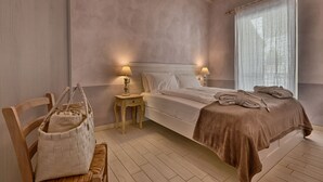 A bedroom with a bed, bedside tables, a wooden chair, and a woven basket. - Apartment with breakfast - Only Adults (Tignale)