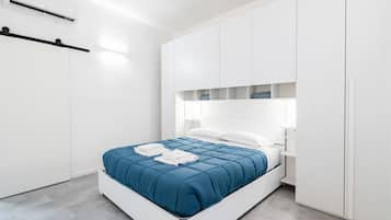 Une chambre moderne avec un lit, une armoire blanche et des étagères intégrées.