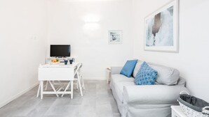 A modern living room with a grey sofa, a white TV stand, and a framed picture on the wall. - GuestHost - Bright and functional 35 sqm apartment, able to accommodate up to 2 people, located on the first floor (without elevator) of a building within Gioberti district. The property is located in a lively neighborhood, full of services and well serv (Firenze)