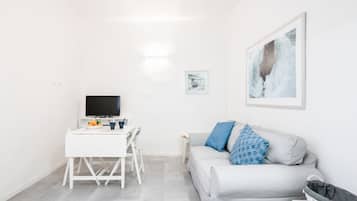 Un salon moderne avec un canapé gris, un meuble TV blanc et un tableau encadré accroché au mur.