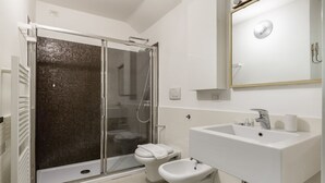 Een moderne badkamer met douche, toilet, toiletbril en wastafel.