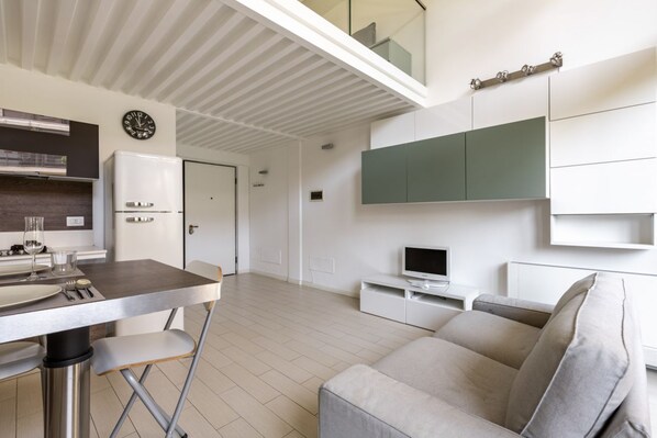 Un espace de vie moderne comprenant un coin repas, un canapé, un téléviseur et une cuisine.