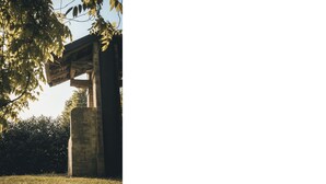 A stone structure with a wooden beam, surrounded by trees and grass. - Agriturismo Il Bio Nonno - Alloggio Bombo (San Matteo della Decima)