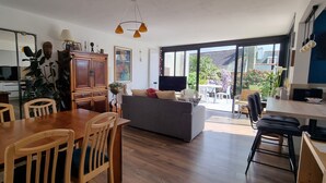 Un vaste espace de vie comprenant une table à manger en bois, un canapé et une grande fenêtre donnant sur l’extérieur.