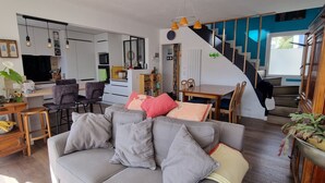 Un salon moderne avec un canapé gris, une table à manger et un escalier menant à la cuisine.