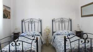 Una habitación con dos camas, cada una con una colcha estampada y un jarrón decorativo entre ellas.