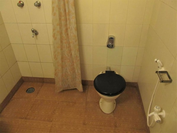 Un baño pequeño con inodoro, ducha y secamanos.