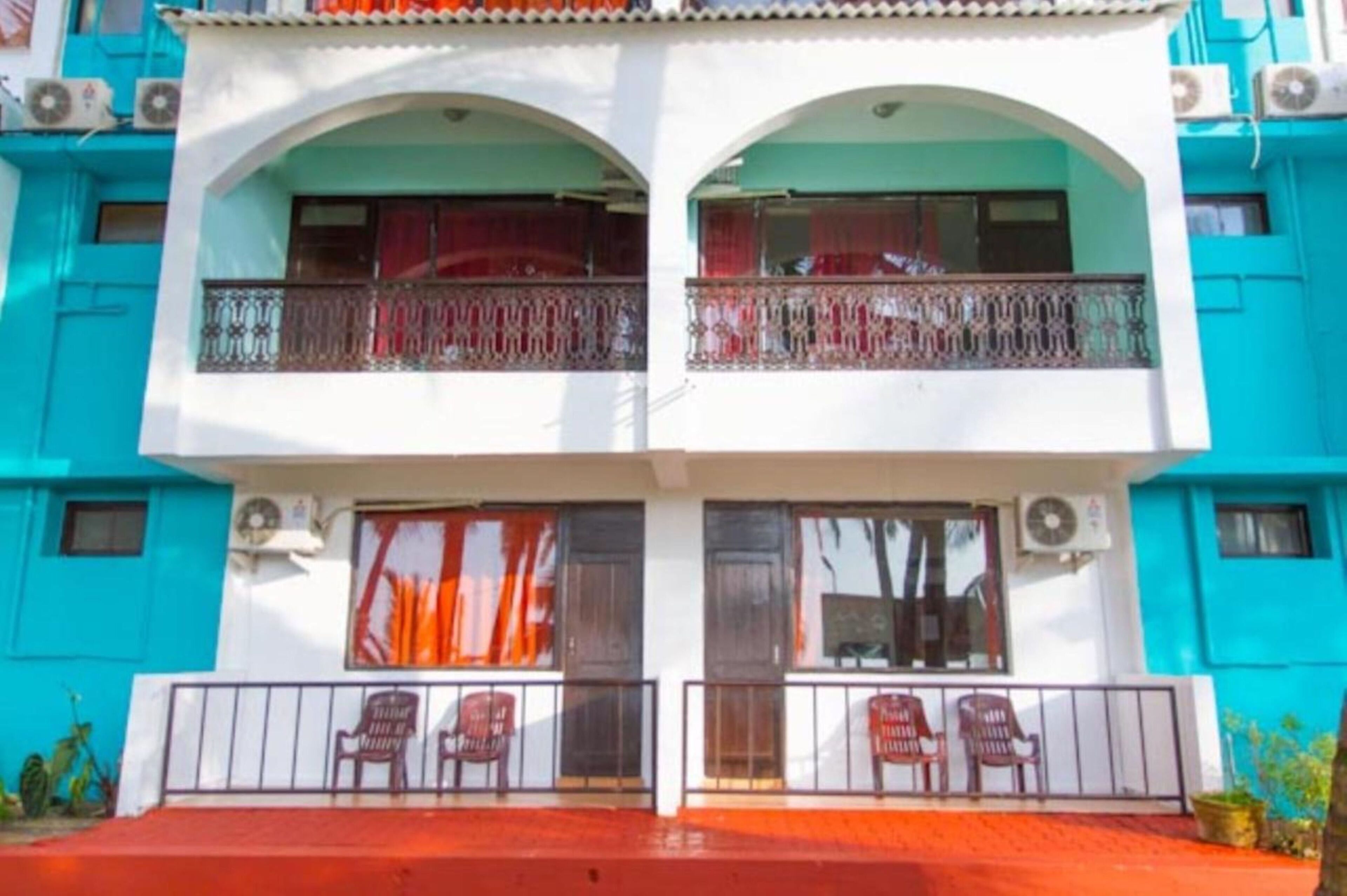 A two-story building with balconies, air conditioning units, and a red carpeted entrance.