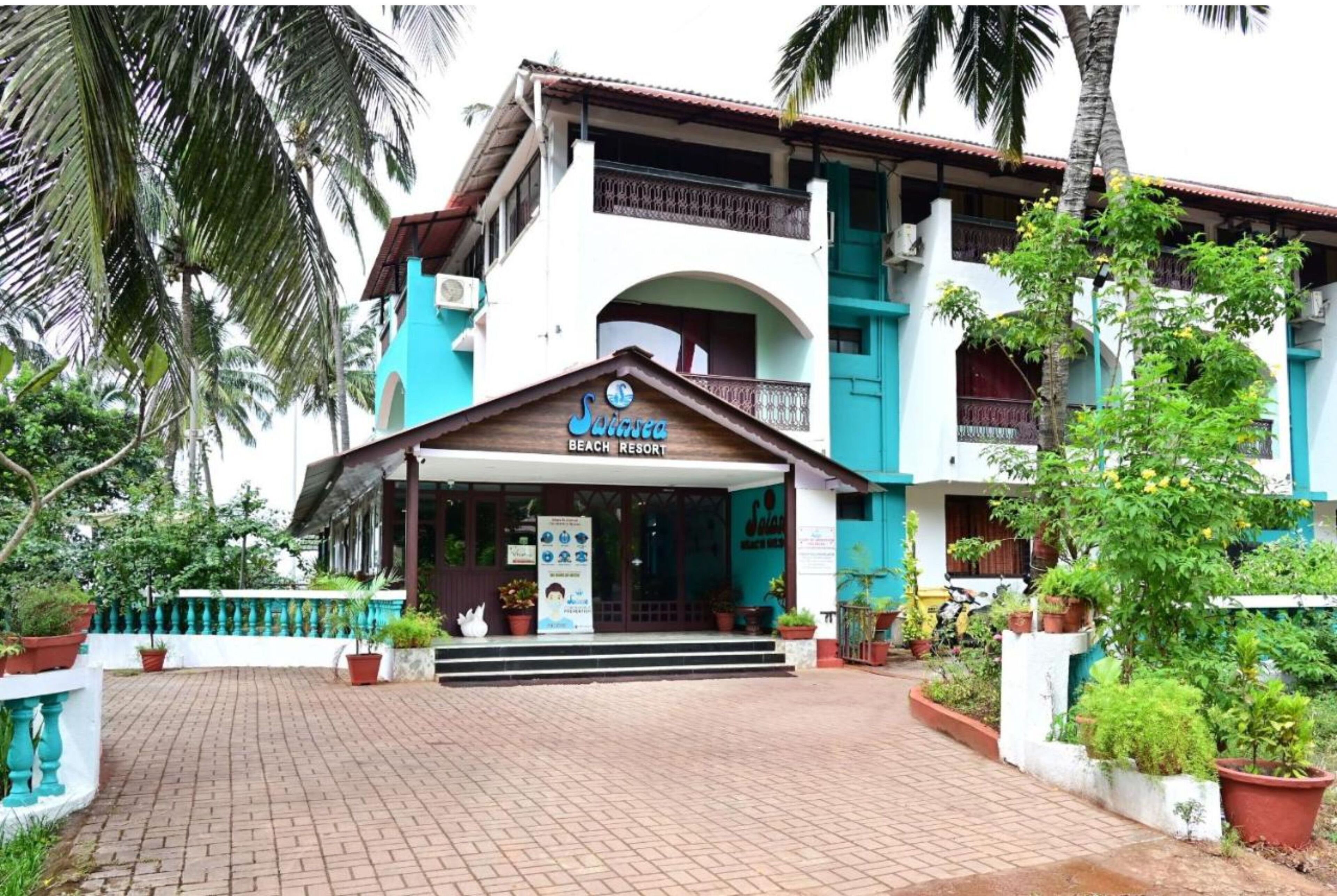 Un edificio de dos plantas con un letrero que dice 'Suicca Beach Resort'.