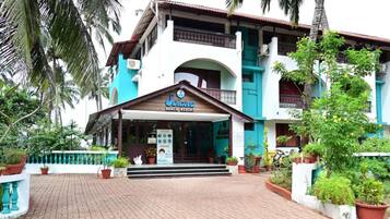 Un edificio de dos plantas con un letrero que dice 'Suicca Beach Resort'.