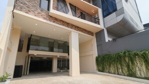 A modern building with a glass entrance, a balcony, and a brick facade. - Flamenco Urban Living (Jakarta)