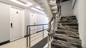 A modern staircase with marble steps and a metal railing, leading to a door marked with the number 307. - Flamenco Urban Living (Jakarta)