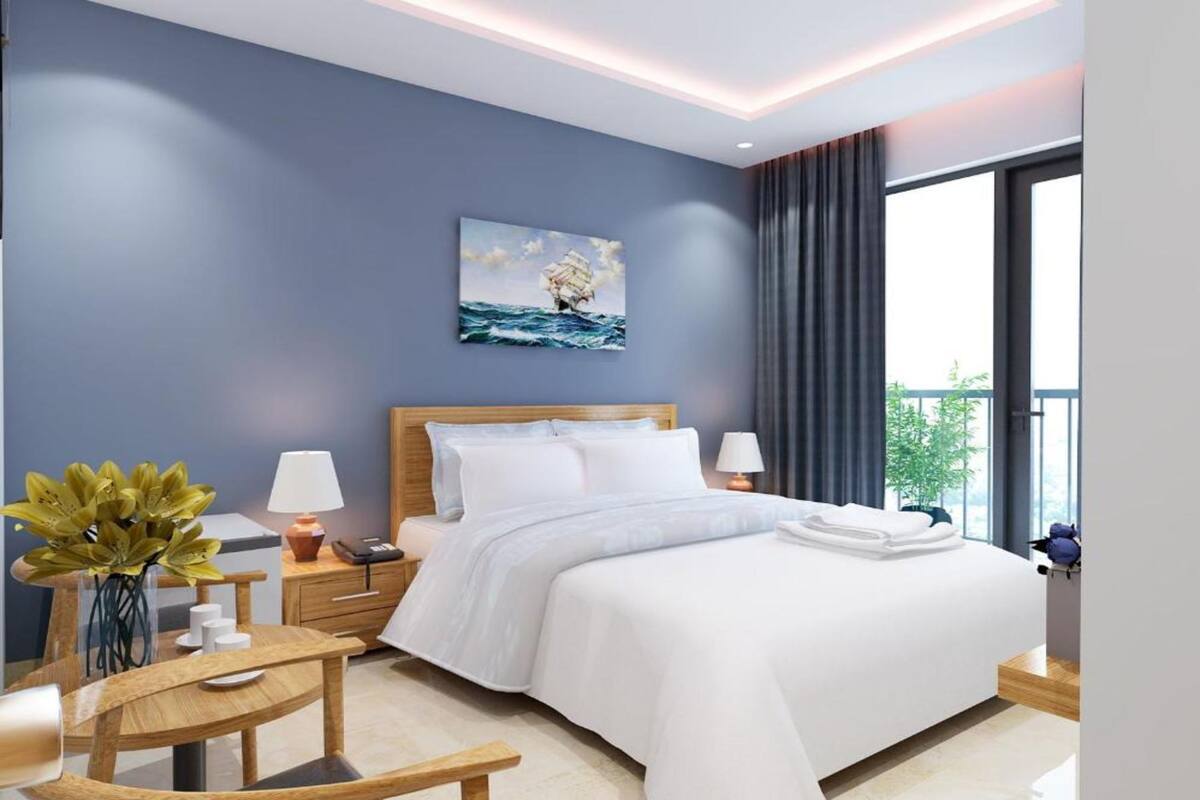 Una habitación de hotel moderna con una cama grande, un escritorio con silla, un jarrón de flores y un cuadro de un barco en la pared.
