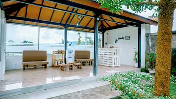 Uma área de estar coberta ao ar livre, com mobiliário de madeira, um armário branco e vista para a água.