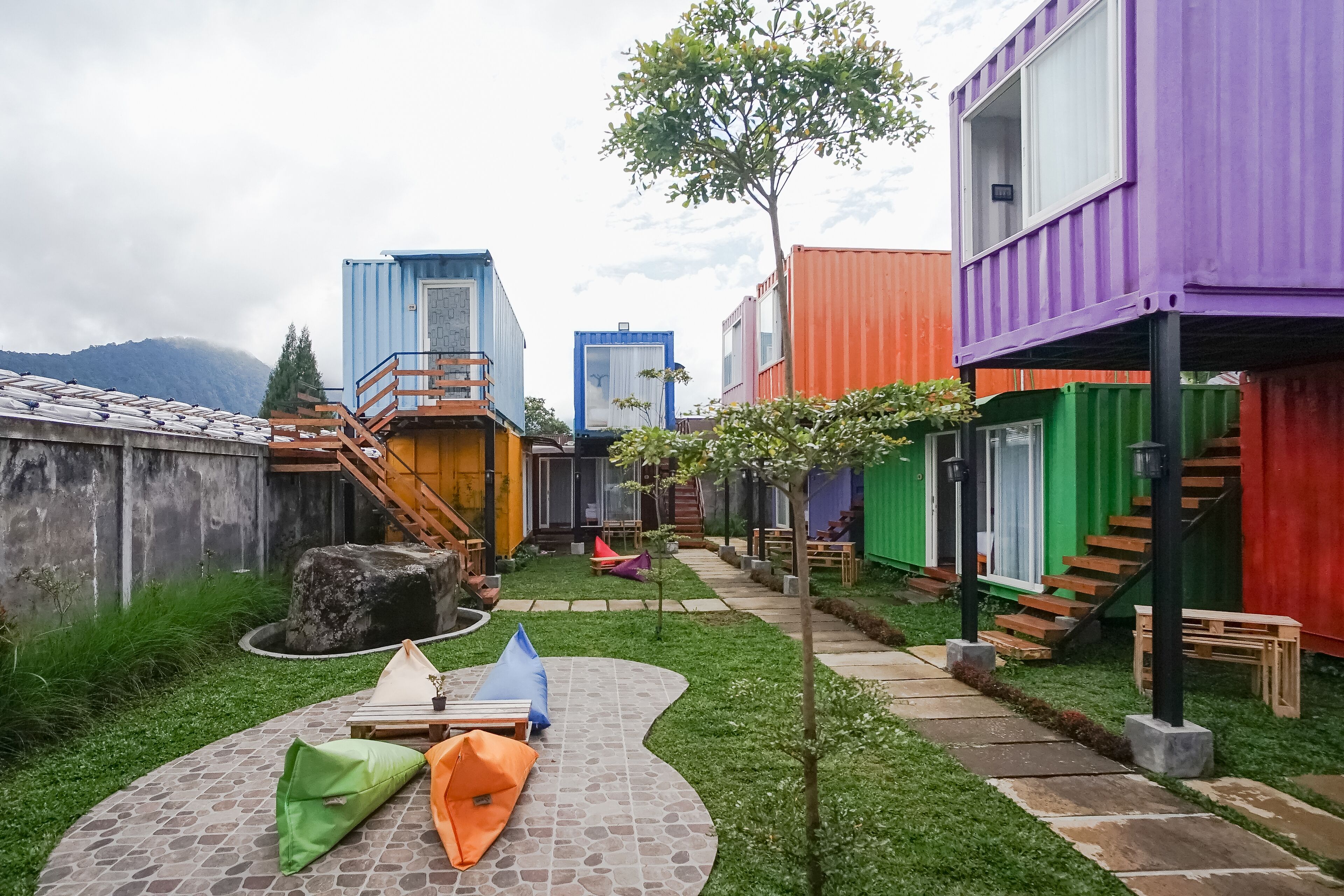 A courtyard with colorful shipping containers used as buildings, a stone pathway, and outdoor seating.