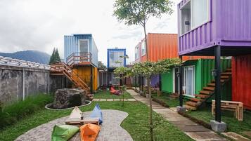 Un patio con contenedores de carga de colores empleados como edificios, un camino de piedra y mobiliario exterior.