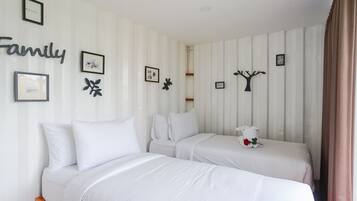 Habitación de hotel con dos camas, ropa blanca y una pared decorada con cuadros y un cartel que dice 'Familia'.