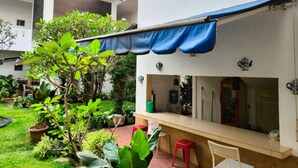 A patio area with a covered seating area, a small table, and potted plants. - Roemah Moesi Medan (Medan)