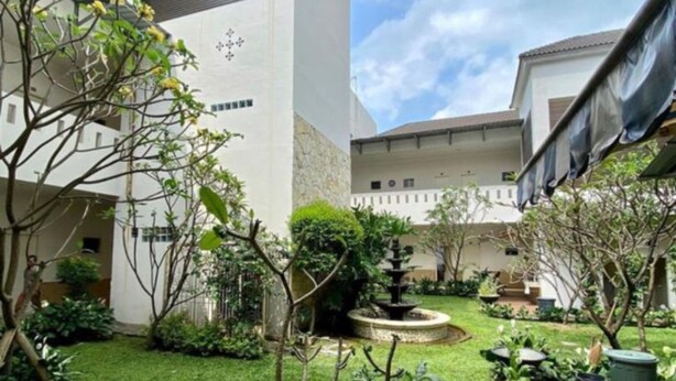 A courtyard with a fountain, surrounded by greenery and white buildings. - Roemah Moesi Medan (Medan)