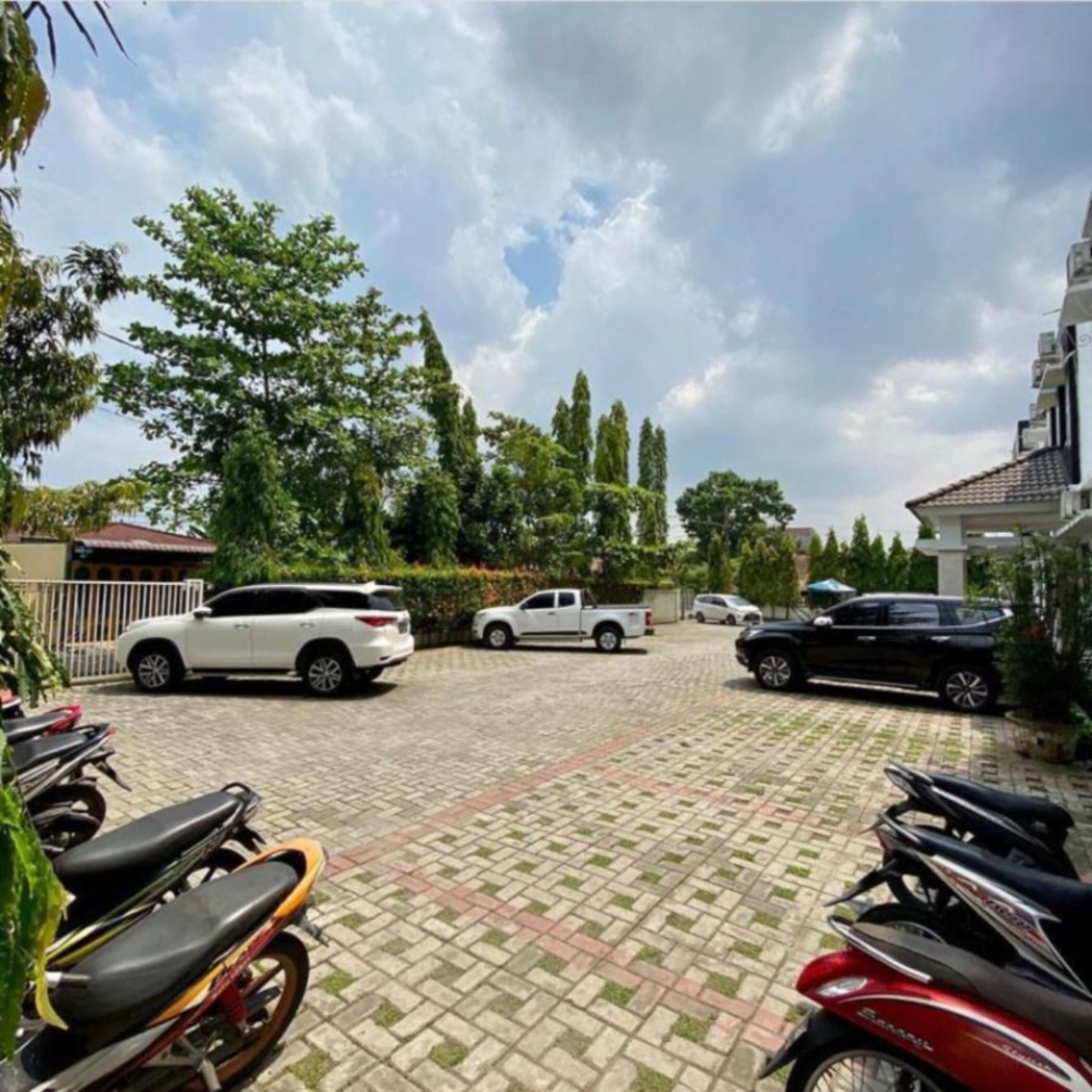 En asfalterad parkeringsplats med flera bilar och motorcyklar parkerade.