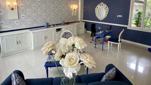 A modern living room with a sofa, a coffee table, and a vase of white flowers. - Roemah Moesi Medan (Medan)