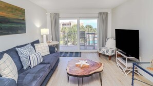 Ein Wohnzimmer mit Sofa, Couchtisch, Fernseher und einem Balkon mit Aussicht.