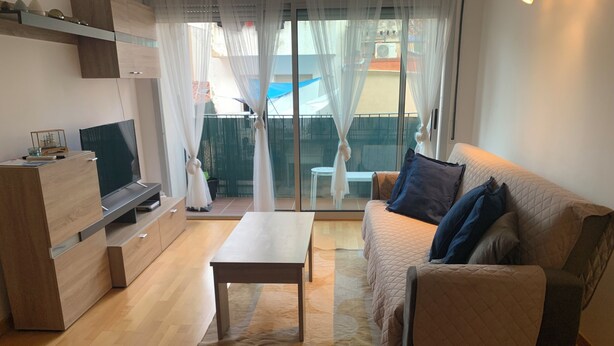 Una sala de estar moderna con sofá, una mesa de centro, televisor y puerta corrediza de vidrio que da a un espacio exterior.