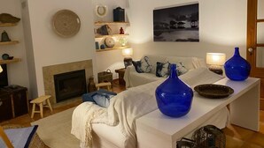 Una sala de estar acogedora con chimenea, un sofá, una mesa de centro y elementos decorativos.