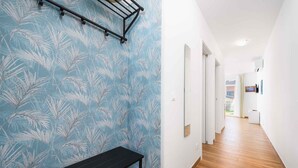 A hallway with a patterned wall, a black bench, and a wooden floor. - Holiday apartment with internet and air conditioning near the sea (Umag)