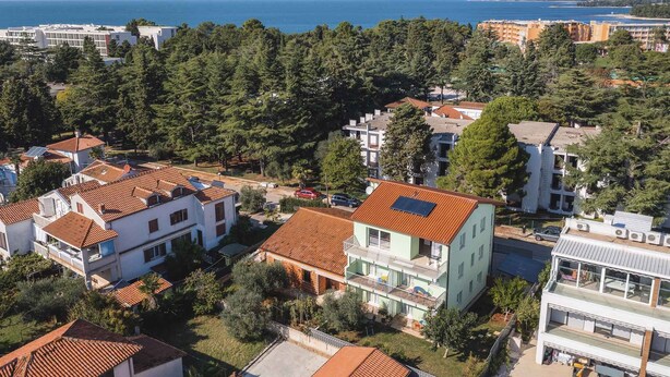 A residential area with houses featuring red-tiled roofs, surrounded by dense greenery and a view of the sea. - Holiday apartment with internet and air conditioning near the sea (Umag)