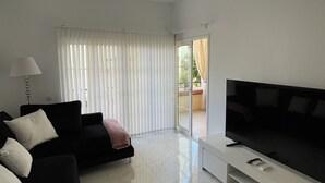 Ein modernes Wohnzimmer mit Flachbildfernseher, schwarzem Sofa und Deckenventilator.
