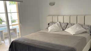 Ein modernes Schlafzimmer mit einem großen Bett, Blick ins Freie und einem klaren, minimalistischen Design.