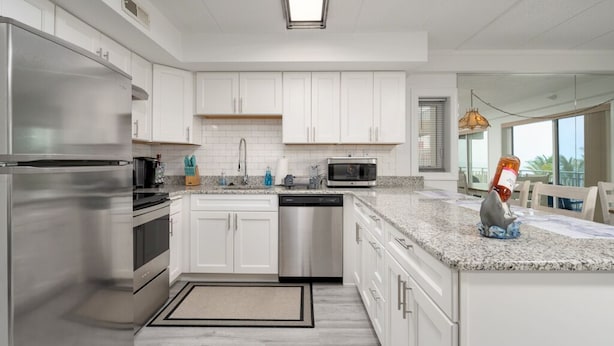 A modern kitchen with white cabinets, stainless steel appliances, and a granite countertop. - Two Bedroom Condo With Great Side View of the Ocean (Ocean City)