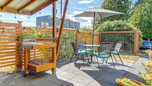 A patio area with a table and chairs, a wooden fence, and potted plants. - Seattle Garden Retreat: Walk to Water & Shops! (Seattle)