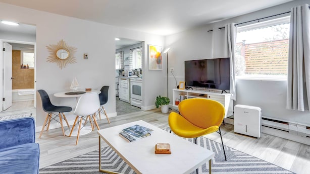 A modern living room with a dining area, a TV, and a kitchen in the background. - Seattle Garden Retreat: Walk to Water & Shops! (Seattle)