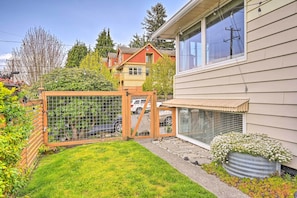 Stroll through the serene front yard, featuring a small lawn and a charming planter with white flowers.