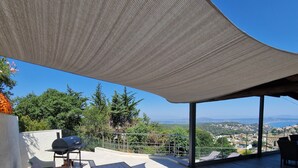 Un patio exterior con una zona de estar cubierta, una mesa y una parrilla.