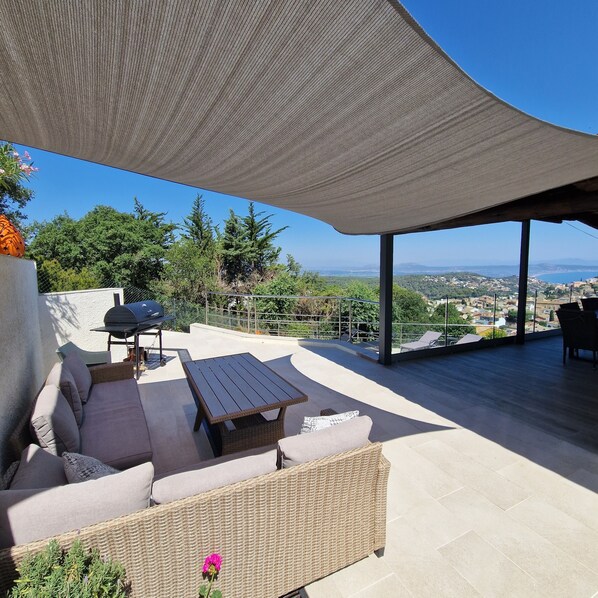 An outdoor patio with a covered seating area, a table, and a grill.