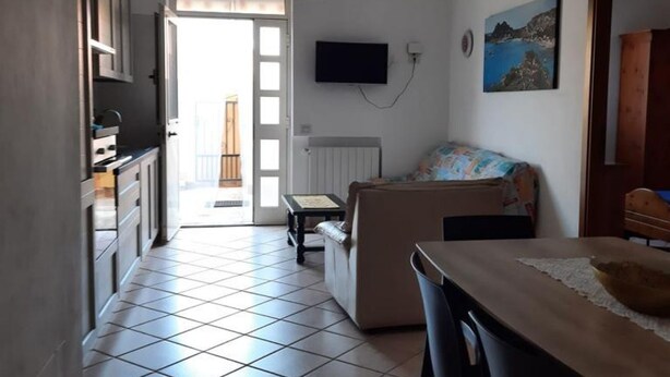Um espaço de estar compacto com cozinha compacta, televisão na parede e um quadro sobre o sofá.