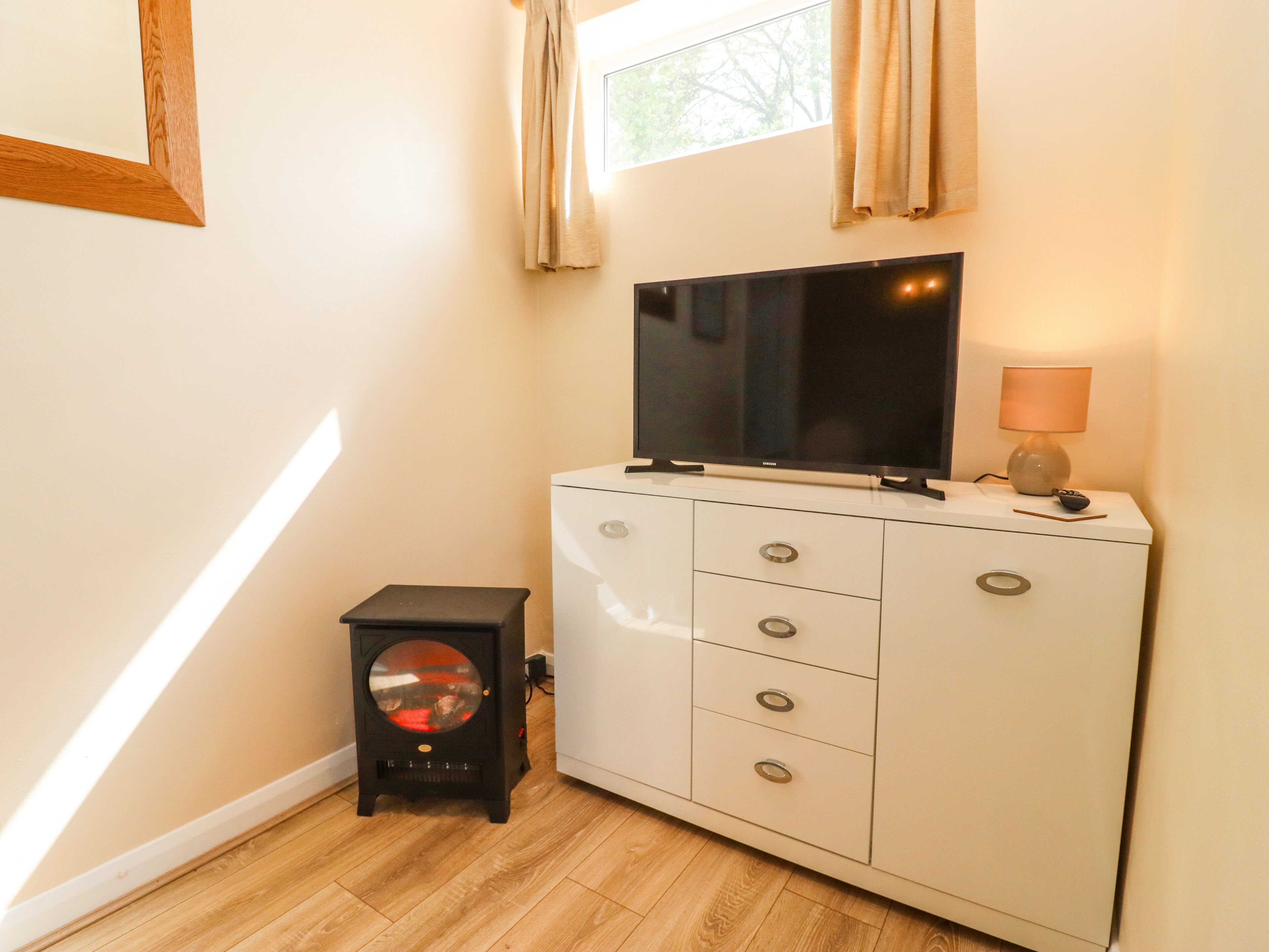 A bedroom with a TV on a cabinet, a lamp, and a heater.