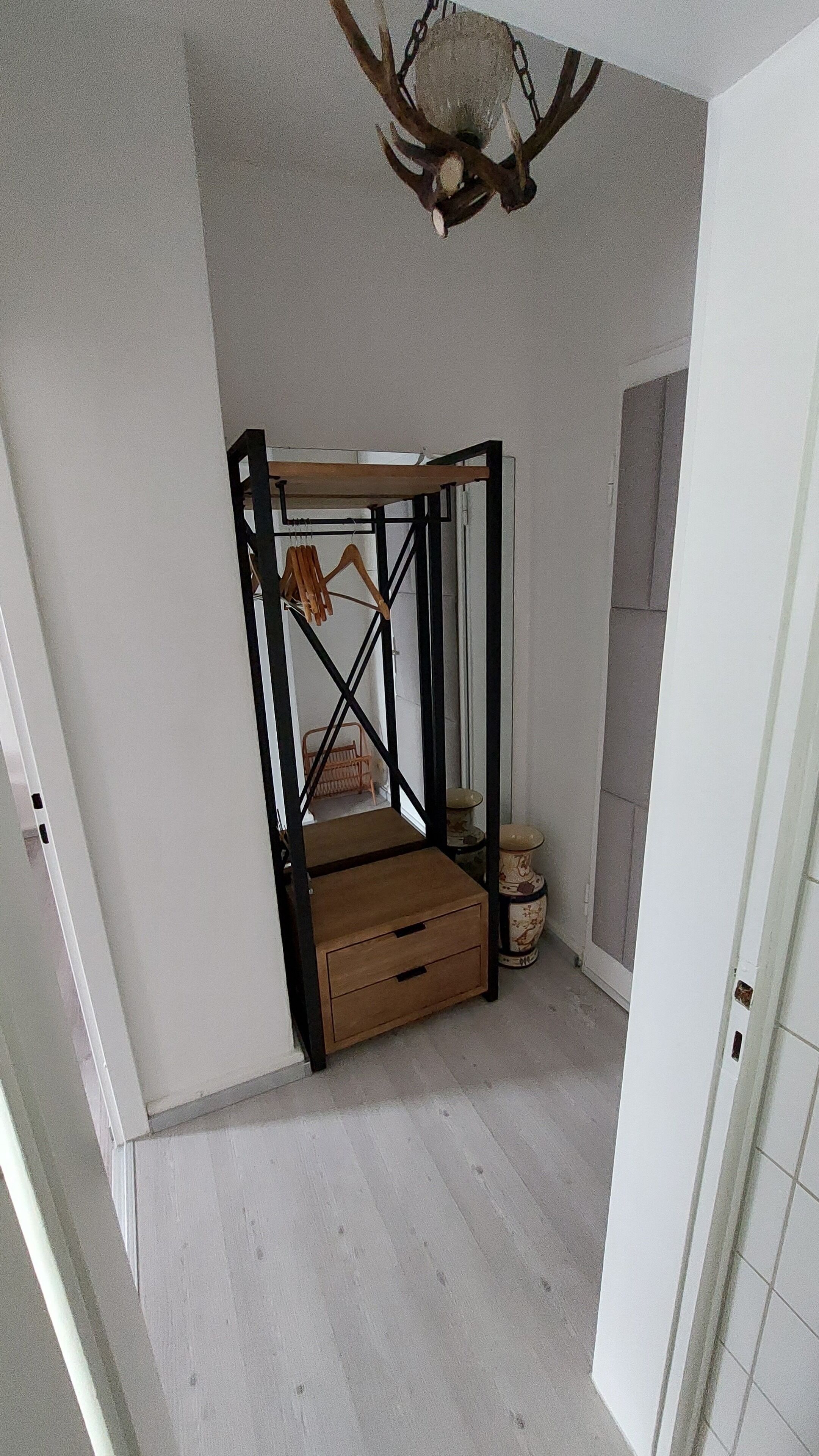 Ein Zimmer mit einem Bettgestell, einer kleinen Holzkiste und einem dekorativen Deckenornament.