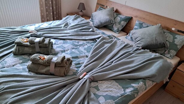 A neatly made bed with a floral patterned bedspread, two pillows, and a folded blanket. - 5 km from the center, 1 km from the train station and 11 km from Baden-Airpark (Baden-Baden)
