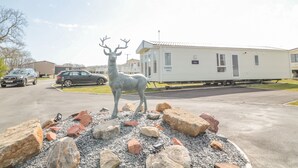 A mobile home with a deer statue in the driveway.