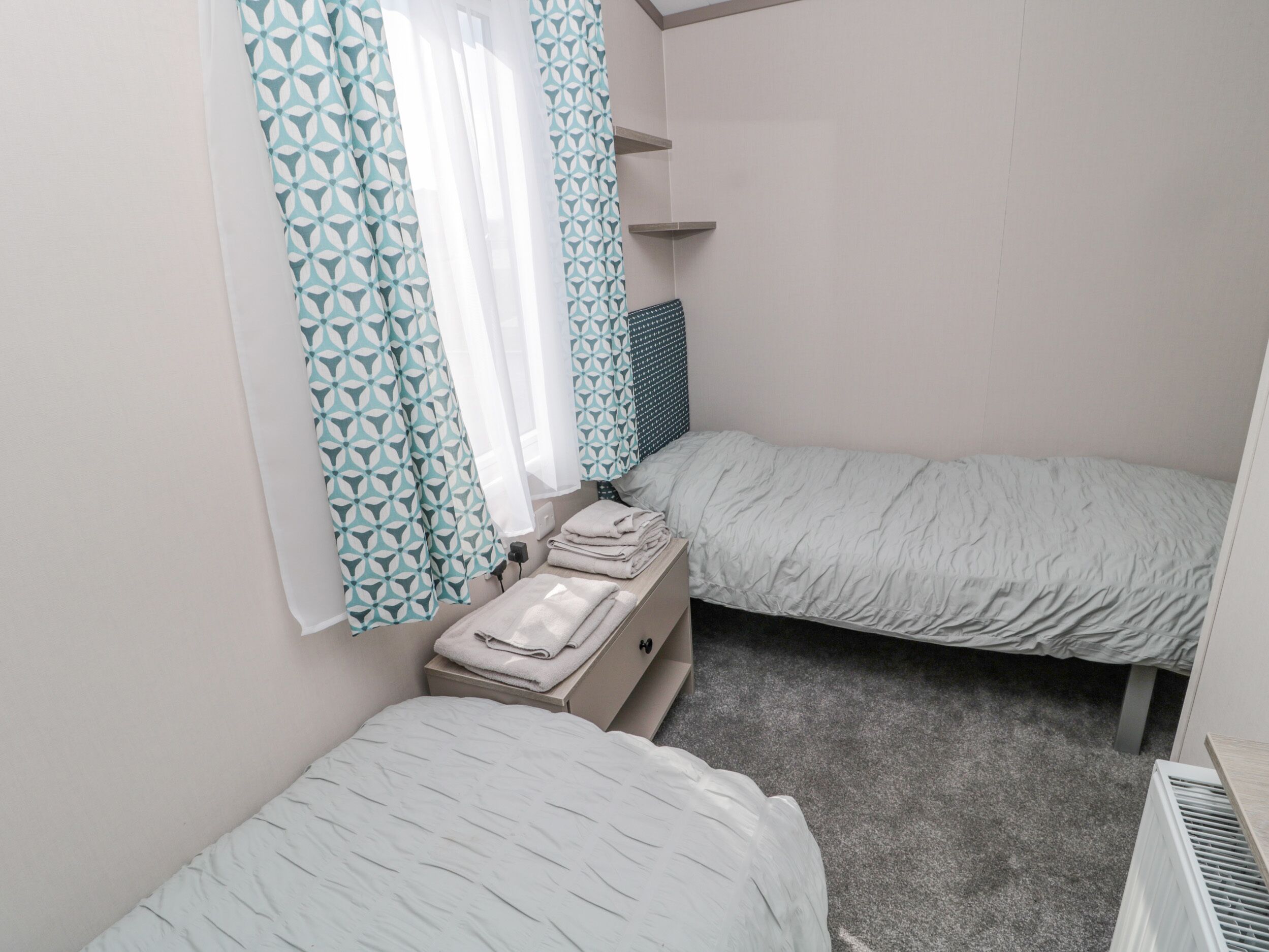 Et lille, rent værelse med to senge, et lille bord og en radiator.