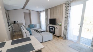 A modern living room with a sofa, a dining table, a TV, and a fireplace.
