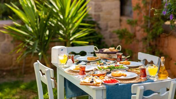 A table set outdoors with various dishes, drinks, and a bottle of olive oil. - Trend Cunda Otel (Ayvalik)