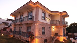 A two-story hotel with a stone facade, multiple balconies, and outdoor seating. - Trend Cunda Otel (Ayvalik)