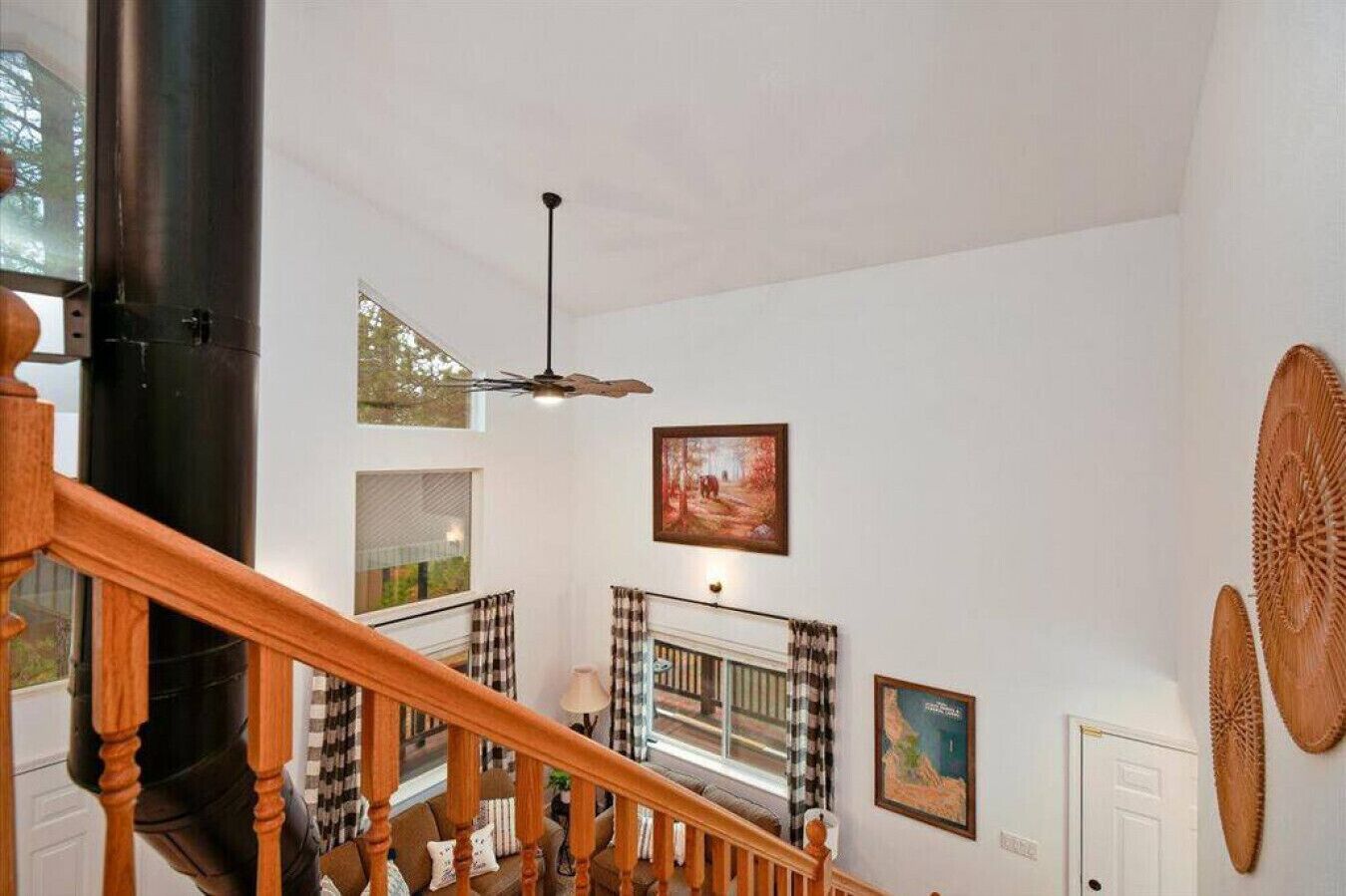 Un intérieur spacieux avec un plafond haut, un escalier doté de rampes en bois et une grande colonne noire.